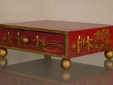 une boîte rouge ornée de motifs dorés, posée sur une table