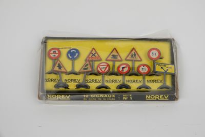 une boîte contenant des panneaux de signalisation miniatures posée sur une surface blanche