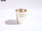 une tasse en argent posée sur une surface blanche
