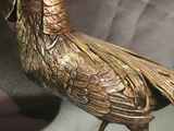a bronze bird that is sitting on a table