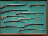 many different types of guns displayed in a display case