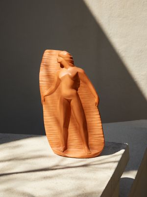 une petite sculpture représentant une femme debout sur une table