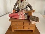a figurine of a woman sitting at a sewing machine