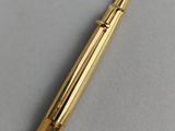 a close up of a gold colored fountain pen on a white surface