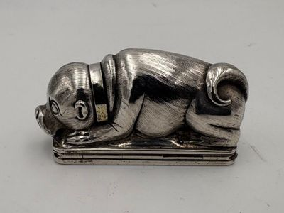 a silver figurine of a dog laying on top of a book