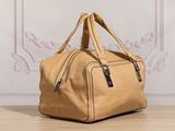 a tan leather bag sitting on top of a wooden table