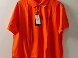un polo orange suspendu à un cintre accroché au mur