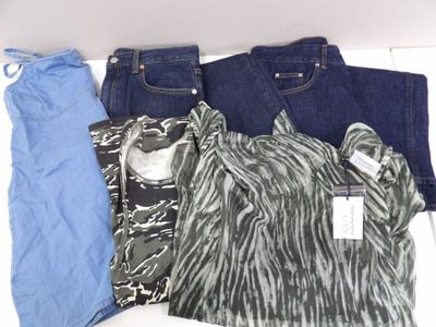 trois paires de jeans et une chemise posées sur une table