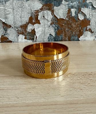 a close up of a gold bracelet on a wooden table