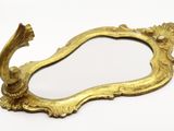 a gold mirror with a bird on it on a white surface