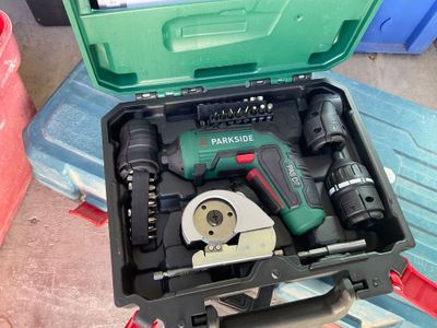 une boîte à outils verte posée par terre, contenant des outils