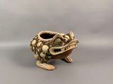 une petite grenouille en céramique au long cou et aux longues pattes