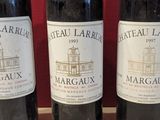 three bottles of wine sitting on a wooden table