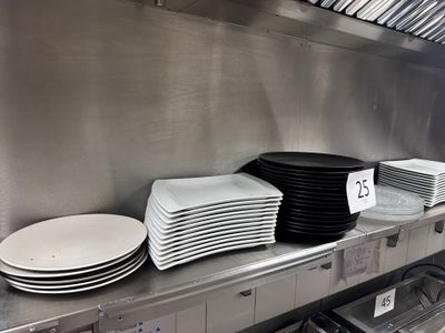 Plusieurs assiettes sont empilées sur une étagère métallique dans une cuisine