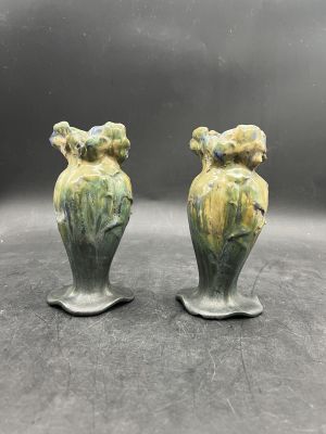 une paire de vases en céramique verts ornés d'oiseaux, posés sur une table