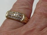 a man ' s hand holding a gold ring with diamonds on it