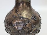 a silver vase that is sitting on a white surface