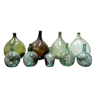 several different colored glass vases are lined up on a white surface