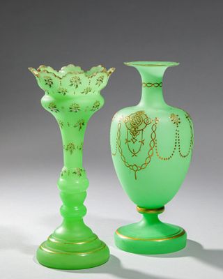 deux vases en verre vert ornés de motifs dorés, posés sur une table
