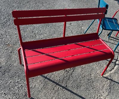 a red bench and a blue chair in a parking lot