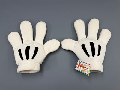 deux gants Mickey Mouse posés sur une surface grise, avec une étiquette