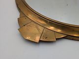 brass plated mirror with scalloped edge on a white surface