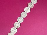 a close up of a bracelet made of silver beads on a pink background