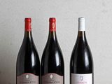 three bottles of wine are lined up on a wooden table