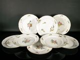 Plusieurs assiettes ornées de motifs floraux sont disposées sur un fond noir