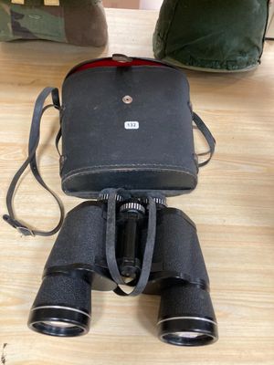 une paire de jumelles noires et un sac vert posés sur une table