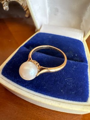 une photo d'une bague en perle dans un écrin posé sur une table