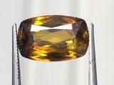 un gros plan d'un diamant jaune tenu par une paire de pinces