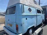 une camionnette bleue avec un toit blanc sur une remorque à plateau