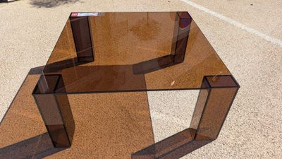a glass table that is sitting in the middle of a parking lot