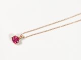 un gros plan d'un collier avec une pierre rose sur une chaîne en or