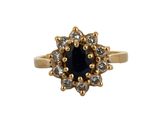 a close up of a gold ring with a black stone surrounded by white diamonds