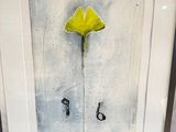 painting of a yellow flower in a white frame on a table