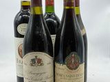 quatre bouteilles de vin sont alignées sur une surface blanche