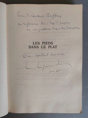 un livre ouvert, dont une page est recouverte d'une écriture manuscrite, posé sur une table