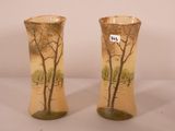 pair of vases with trees painted on them sitting on a table