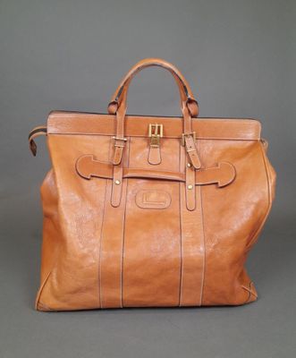 the large brown leather bag is sitting on a gray surface