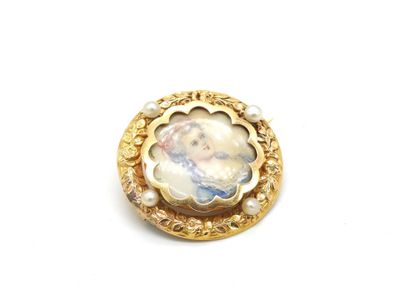 un gros plan d'une broche plaquée or sur laquelle figure le portrait d'une femme