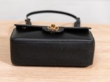 the small black purse is sitting on a wooden table