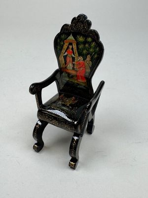 a miniature chair with a painting on the back of it
