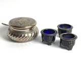 a small silver box with three blue glass cups next to it
