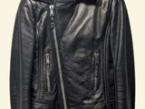 the leather jacket is hanging on a hanger on the wall