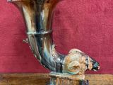 a horn shaped vase sitting on a wooden table