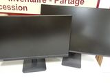 two computer monitors sitting on top of a table in front of a sign
