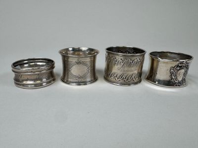 quatre serviettes argentées et un porte-serviettes posés sur une surface blanche