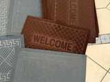several different colored welcome mats on a tiled floor in a bathroom